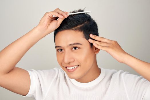 Handsome smiling Asian young man doing modern hairstyle