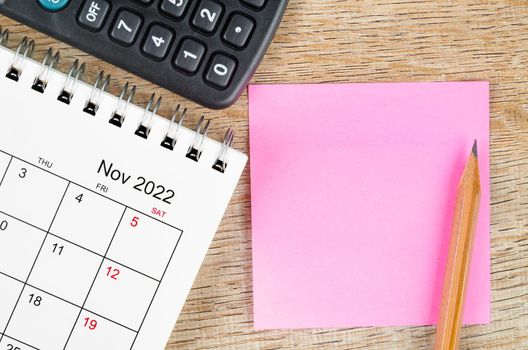 The Blank sticky note on November 2022 desk calendar on wooden background for your text.