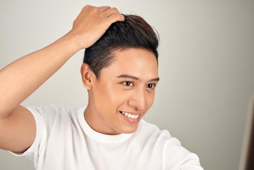 Happy handsome smiling Asian man touching his hair