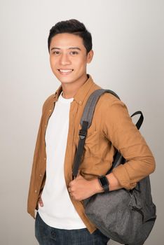 a side view portrait of a smiling student carrying his backpack, isolated on a white background