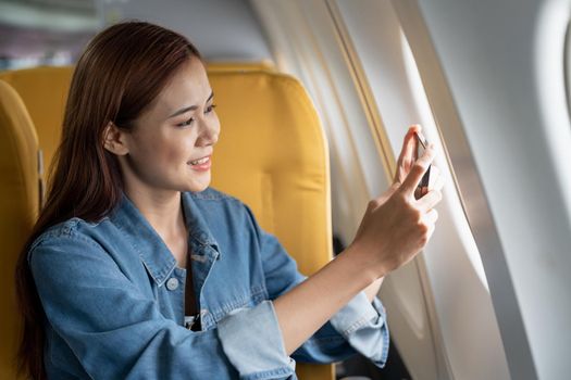 Beautiful Asian woman take a photo with mobile phone in airplane