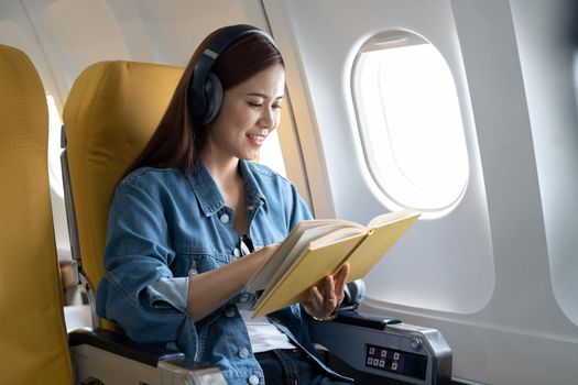 Beautiful asian travel woman reading a book in airplane