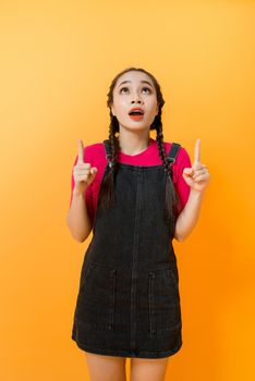 Portrait of Asian woman pointing at something on color background