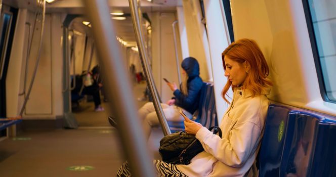 Woman in public transport using smartphone scrolling. Female chatting with friends. Technology and cellphone in the city. Technology content.