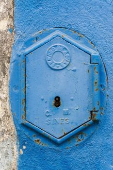 Old rusty blue painted iron lid of a valve box of the SERVICO DE AGUA PUBLIC WATER SUPPLY