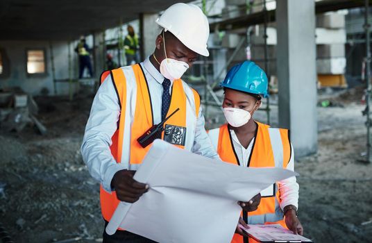 Promoting teamwork promotes productivity. a young man and woman going over building plans at a construction site.