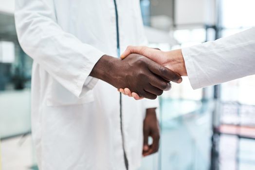Improving clinical performance through teamwork. Closeup shot of two doctors shaking hands in a hospital.
