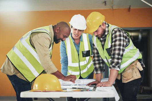 The right plan is a firm foundation for success. a group of builders going over building plans at a construction site.