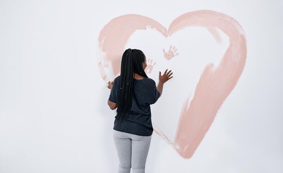 Instead of a Valentines Day card, how about a mural. a young woman painting a heart on a wall.