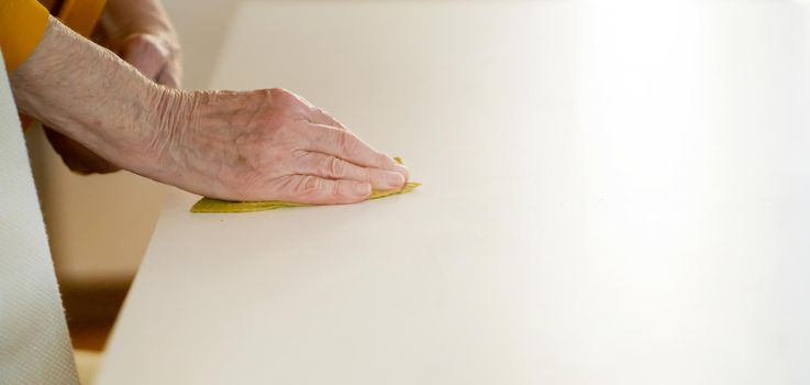 Old woman is cleaning the house, hand with a rag closeup.