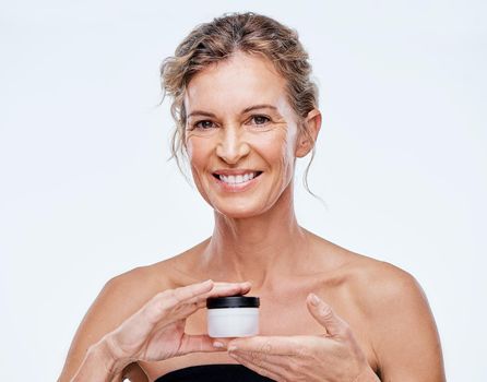 This is my secret. a mature woman holding up a beauty product against a while background.