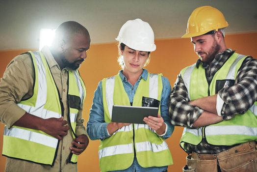 Who needs paper to pull off a winning construction project. a group of builders using a digital tablet while working at a construction site.