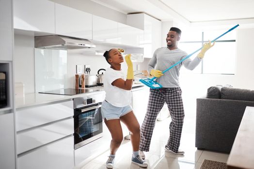 Nothing makes a marriage sparkle like good, clean fun. a happy young couple having fun while cleaning the kitchen at home.