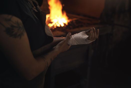 Workplace injury prevention is in your hands. a woman working at a foundry with a bandage wrapped around her hand.
