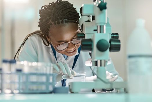 Science is a vital channel of knowledge. a young scientist using a microscope in a lab.