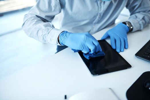 Cleanliness is especially essential during the pandemic. Closeup shot of an unrecognisable businessman cleaning a digital tablet in an office.