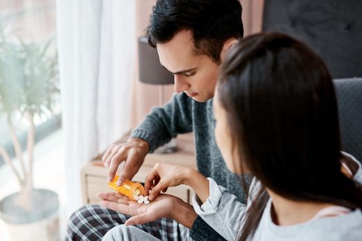 Caring is sharing, except when youve got the flu. a young couple taking medication while recovering from an illness in bed at home.