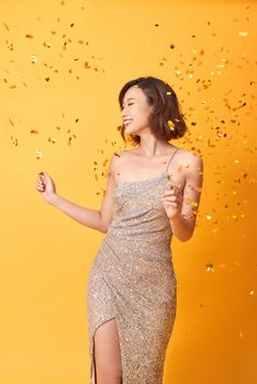 Happy young asian woman in fancy dress with sequins and confetti at party