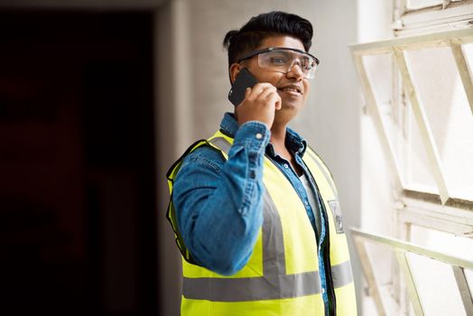 I need your help on this project. a engineer talking on his cellphone while on a construction site.