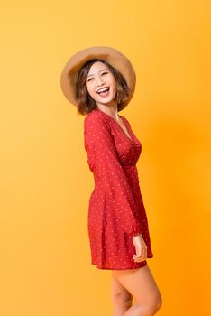 Studio shot of happy energetic asian woman wearing red dress and straw hat over orange background