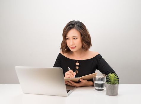 Portrait of young Asian business woman writing at working table.