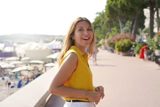 Portrait of hispanic laughing woman with yellow shirt walking on Cannes promenade, France