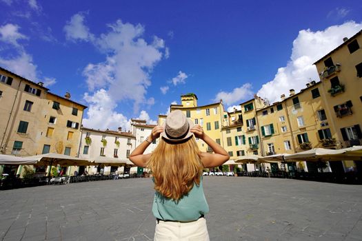 Tourism in Italy. Rear view of young traveler woman visiting the historic city of Lucca in Tuscany, Italy.
