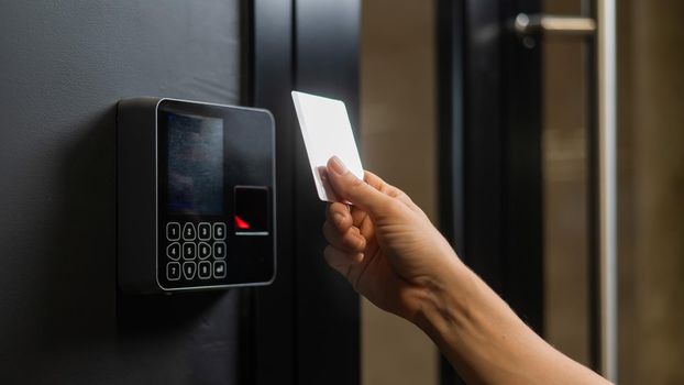 A woman opens the door with a plastic card. Modern keyless entry lock.