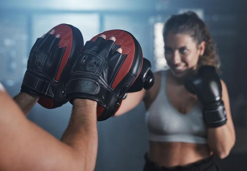 Get punching, get your heart pumping. a young woman practicing with her coach at a boxing gym.