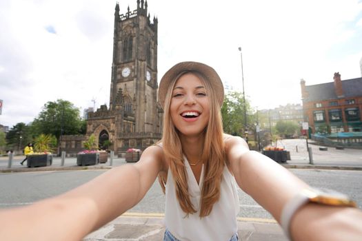 Beautiful girl taking self portrait with Manchester Cathedral on the background, England, United Kingdom