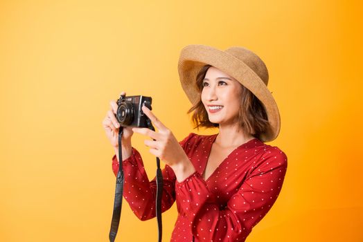 Portrait of fashionable young woman with vintage film camera for travelling concept. Isolated on orange background
