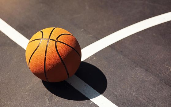 Time to bounce and shoot. Still life shot of a basketball on the ground in a sports court.