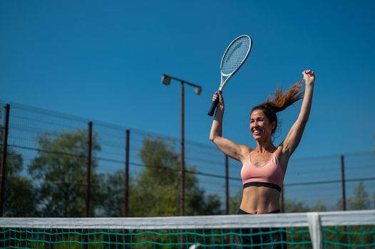 Smiling woman winner in tennis. Happy girl on an outdoor tennis court.