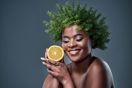 This citrus fruit can prevent a host of skin issues. a beautiful woman holding an orange and wearing a leaf wreath on her head.