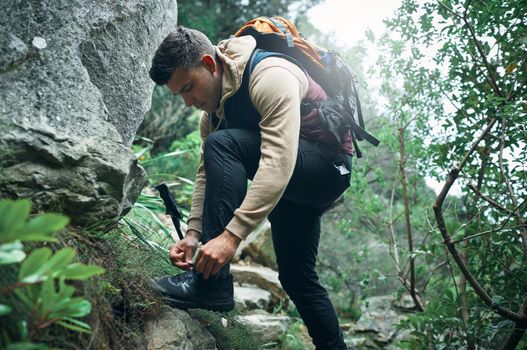 Hike more, worry less. a young man tying his laces while out on a hike.