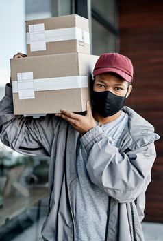 Keeping customers happy at a safe distance. a masked young man delivering a package to a place of residence.