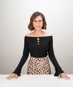 Young Asian business woman standing behind desk and smiling over white background