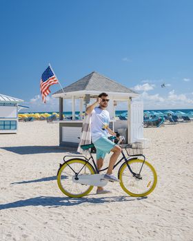 Young men in a swim short on the beach Miami with a bicycle, colorful Miami beach Florida