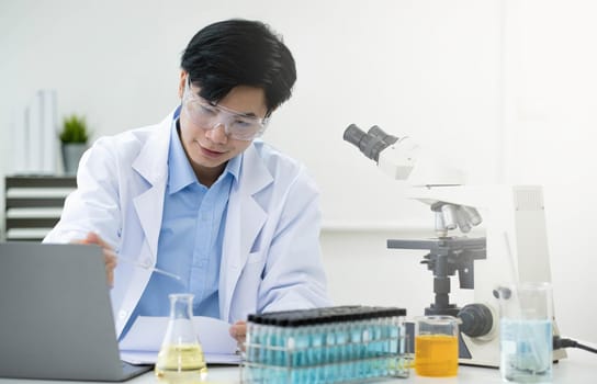 Medical Research Laboratory: Portrait of a Handsome Male Scientist Using Digital Tablet Computer, Analysing Liquid Biochemicals in a Laboratory Flask.