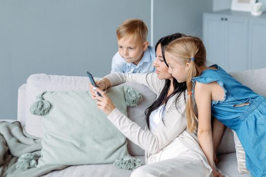 mom with two kids watching videos on her smartphone.