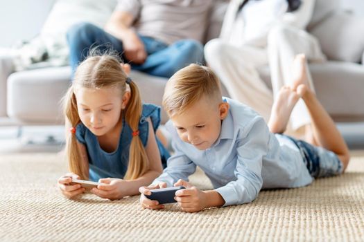 little brother and sister playing entertaining games on their smartphones.