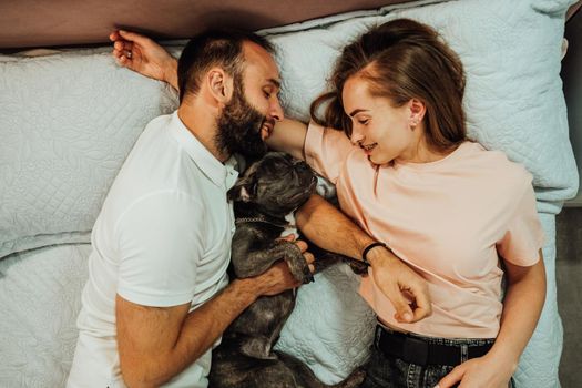 Happy Couple Man and Woman Laying on the Bed with Their Dog, French Bulldog Sweetly Sleeping with Humans