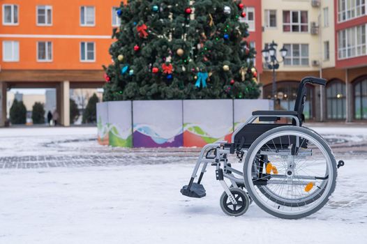 Empty wheelchair on christmas tree background outdoors.