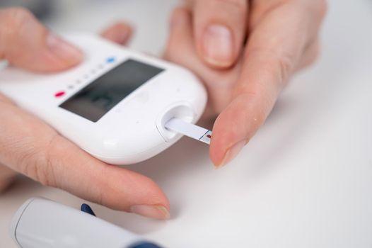 Woman measures blood sugar level with a glucometer.