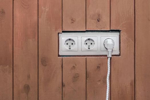 Connect the power and energy plug cable to the outlet on the brown wooden surface background