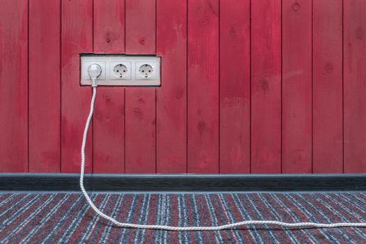 Connect the power and energy plug cable to the outlet on the red wooden wall surface