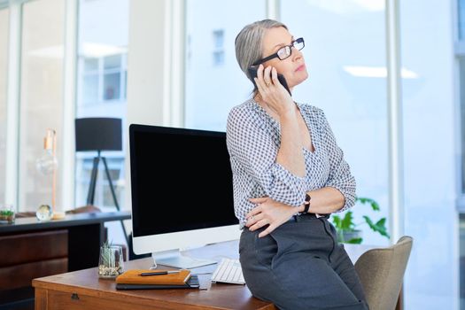 Talking deals over the phone. a mature businesswoman talking on a cellphone in an office.