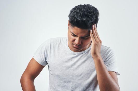 I cant take it anymore. Studio shot of a young man suffering from a headache while standing against a white background.