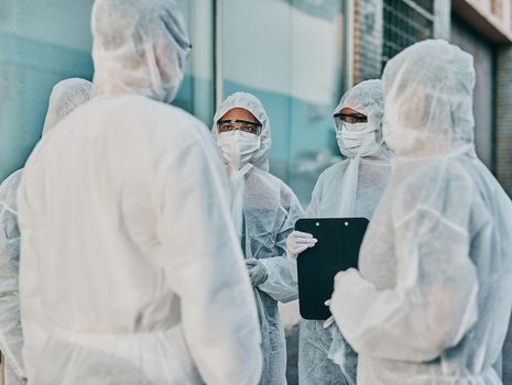 Health and safety personnel in protective gear ready to fight a virus, outbreak or pandemic. Hazmat wearing doctor, nurse and team or group of medical and healthcare professional at a quarantine site