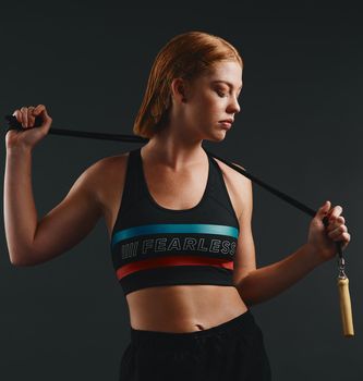 Jumping rope is an excellent endurance activity. Studio shot of a sporty young woman posing with a skipping rope against a black background.